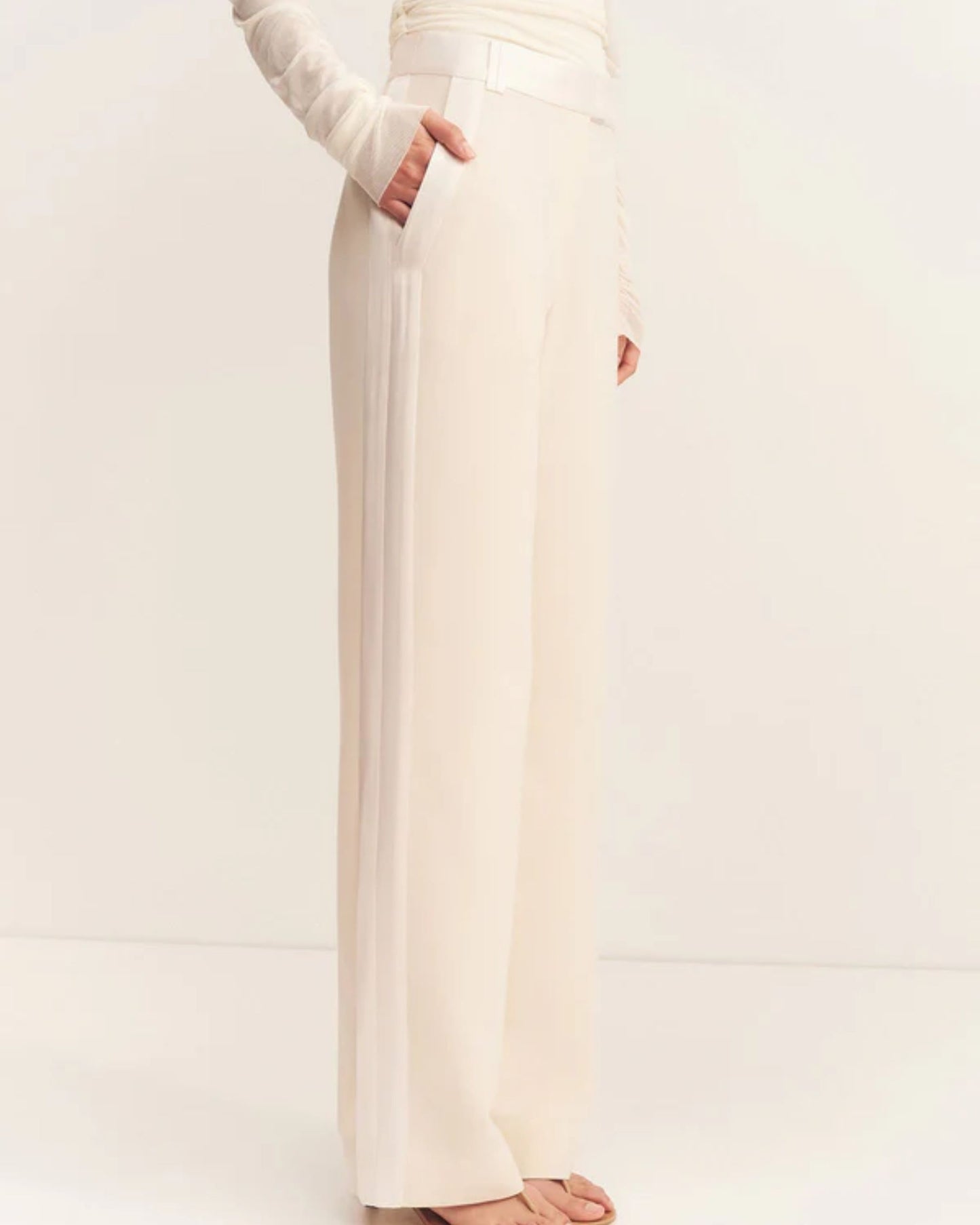 Side view, Adri Tuxedo Side Panel Pants with a contrast satin waistband, side panels, and pockets. Features include a mid-rise fit, knife pleats, jet pockets, and a relaxed straight leg. Available at Georgette bridal boutique in Brussels and online at georgettebridal.com.
