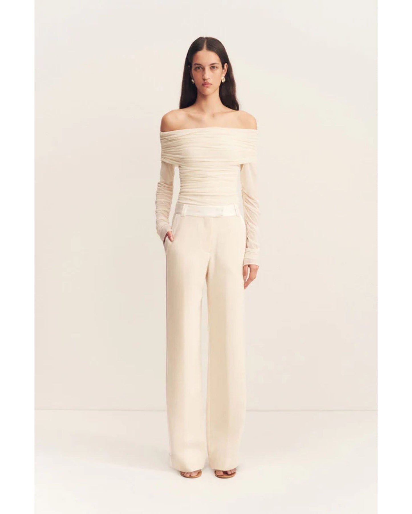 Model wearing the Adri Tuxedo Side Panel Pants with a contrast satin waistband, side panels, and pockets. Features include a mid-rise fit, knife pleats, jet pockets, and a relaxed straight leg. Available at Georgette bridal boutique in Brussels and online at georgettebridal.com.