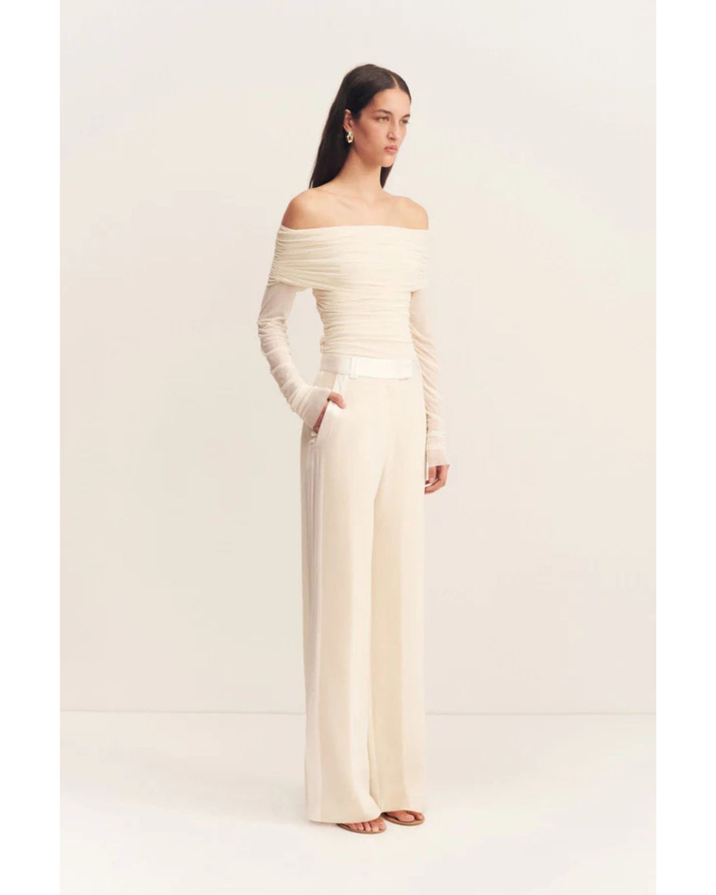 Model wearing the Adri Tuxedo Side Panel Pants with a contrast satin waistband, side panels, and pockets. Features include a mid-rise fit, knife pleats, jet pockets, and a relaxed straight leg. Available at Georgette bridal boutique in Brussels and online at georgettebridal.com.