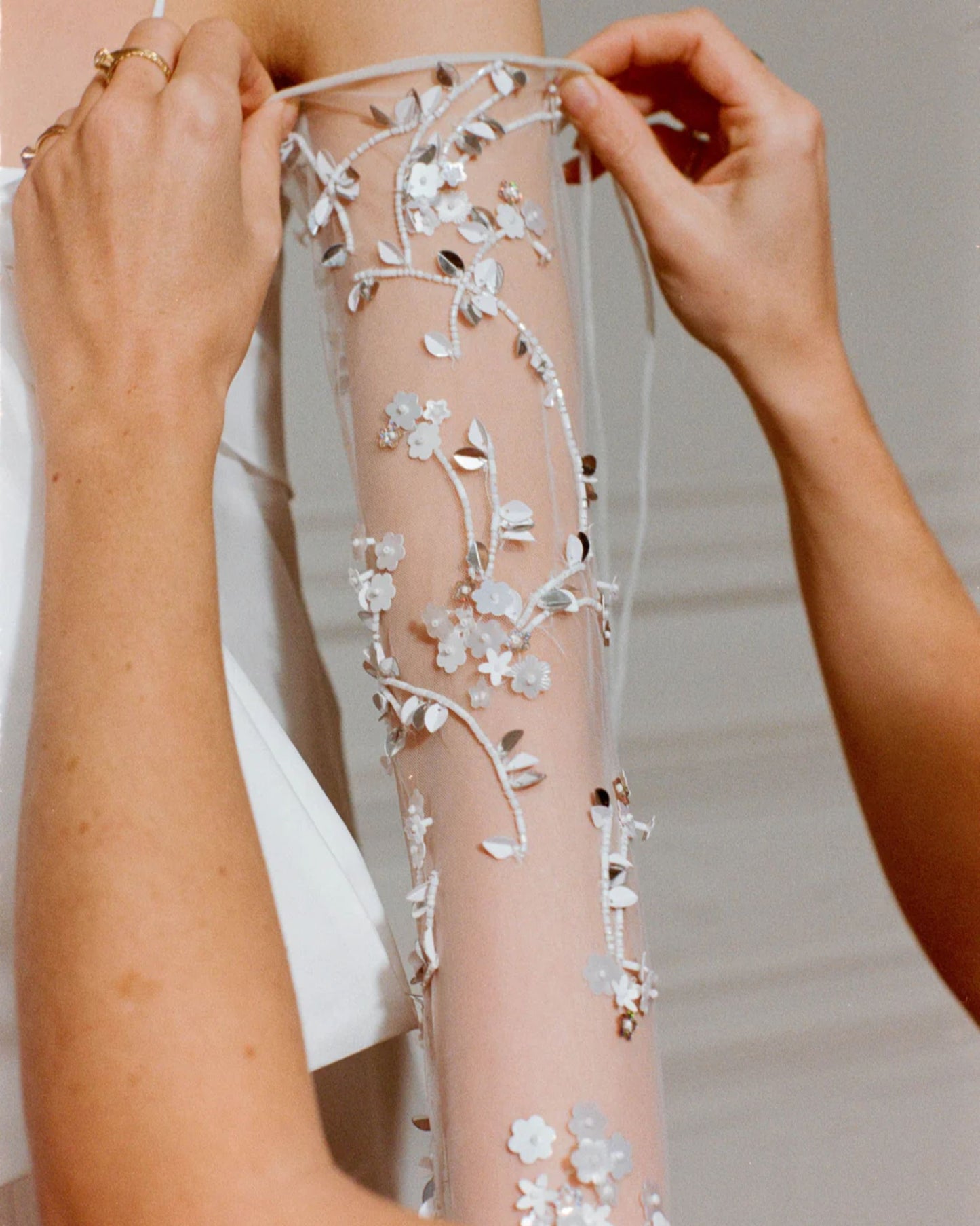 Close-up of the Bernadette bridal gloves with hand-embroidered pearls. The tulle fabric covers your arms elegantly, finished with a knotted little bow above the elbow to ensure elegance at all times.
Available at Georgette bridal boutique in Brussels and online at georgettebridal.com.