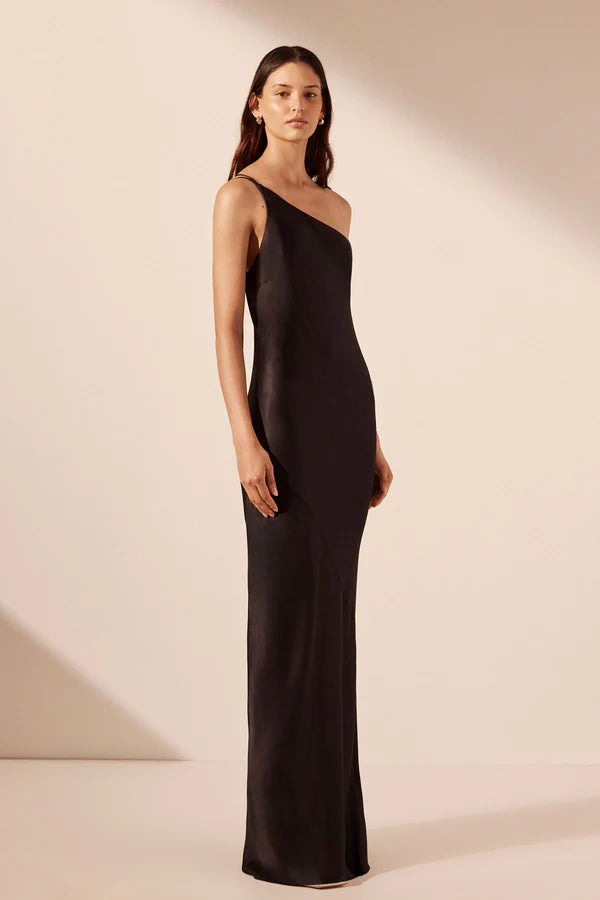 Model wearing a striking black asymmetrical one-shoulder maxi dress with an open cowl back, made from sustainable LENZING™ ECOVERO™ viscose with a satin finish. Available at Georgette bridal boutique in Brussels and online at georgettebridal.com.