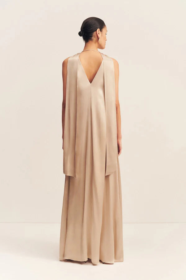 Back view, elegant golden maxi dress with a deep plunging neckline and draped scarf detail, made from satin-finish LENZING™ ECOVERO™ viscose for a sophisticated, fluid look. Available at Georgette bridal boutique in Brussels and online at georgettebridal.com.