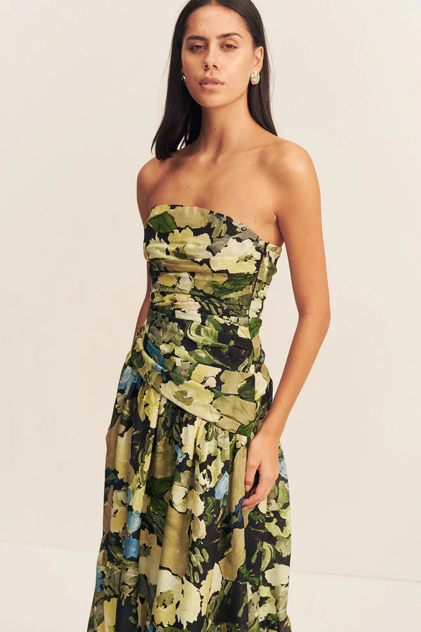 Close-up of a strapless tiered maxi dress in a sheer Botanical Floral print, featuring a softly draped asymmetrical bodice, full tiered skirt, and invisible side zip. Crafted from a linen and TENCEL™ blend. Available at Georgette bridal boutique in Brussels and online at georgettebridal.com.