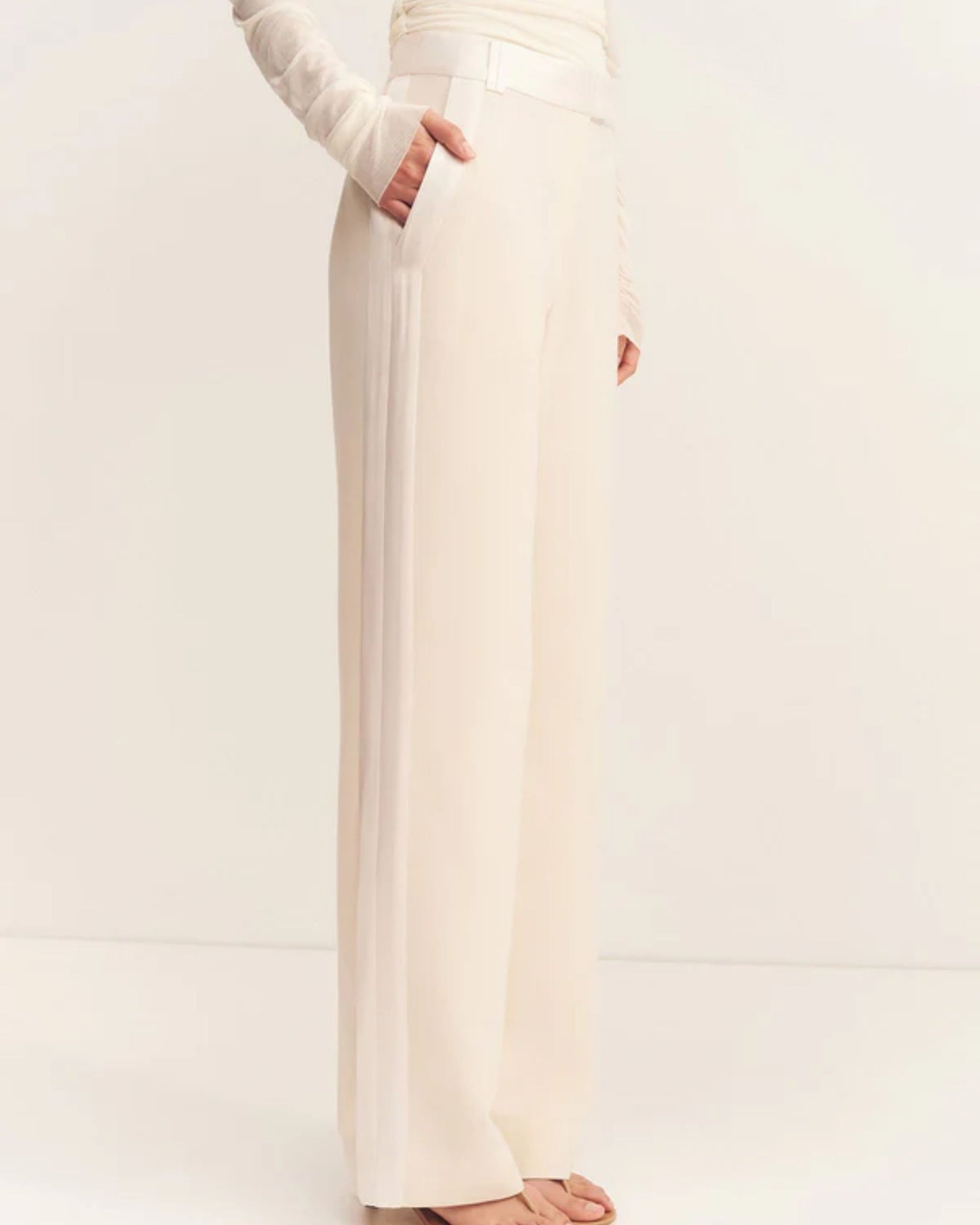 Side view, Adri Tuxedo Side Panel Pants with a contrast satin waistband, side panels, and pockets. Features include a mid-rise fit, knife pleats, jet pockets, and a relaxed straight leg. Available at Georgette bridal boutique in Brussels and online at georgettebridal.com.