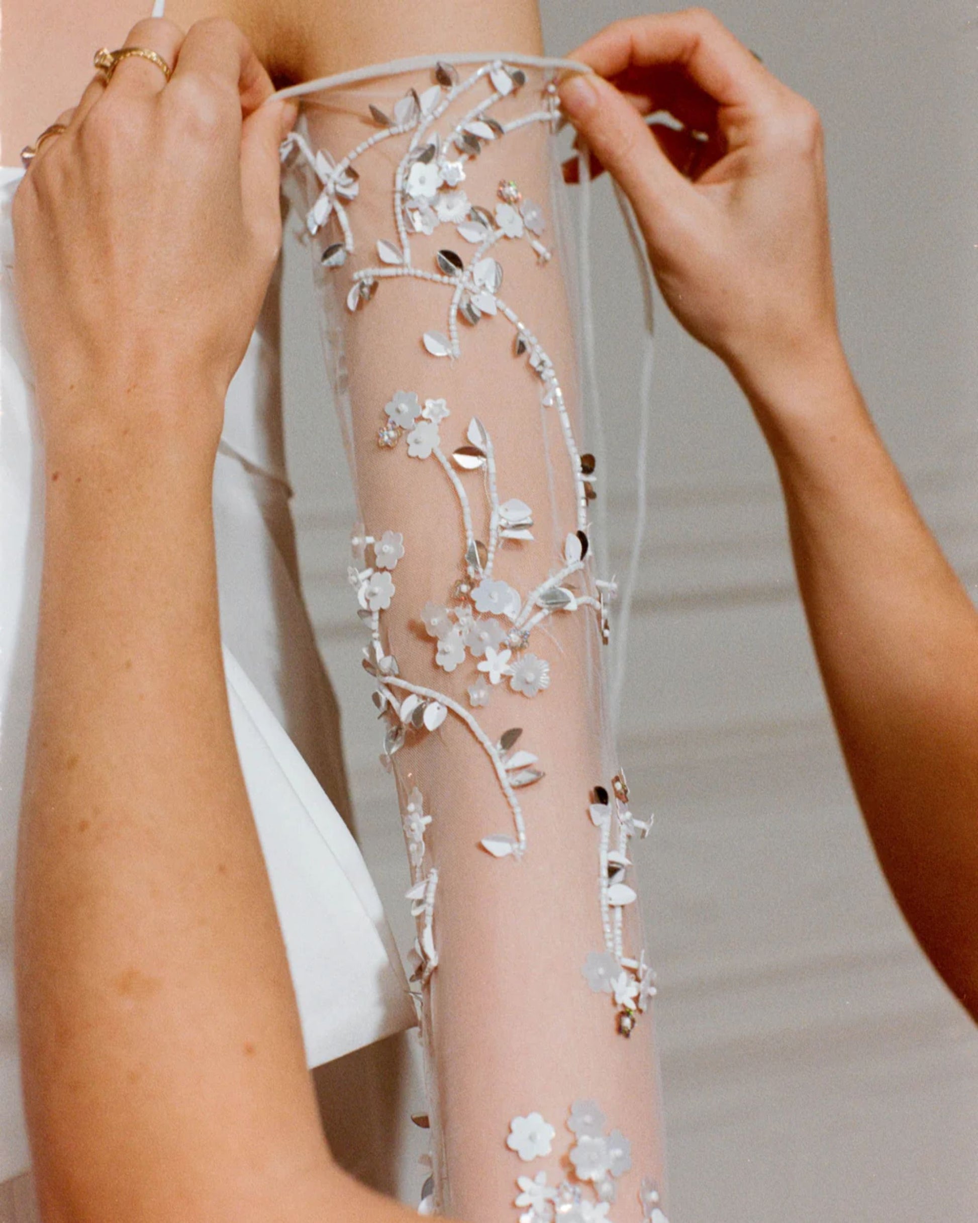 Close-up of the Bernadette bridal gloves with hand-embroidered pearls. The tulle fabric covers your arms elegantly, finished with a knotted little bow above the elbow to ensure elegance at all times. 
Available at Georgette bridal boutique in Brussels and online at georgettebridal.com.