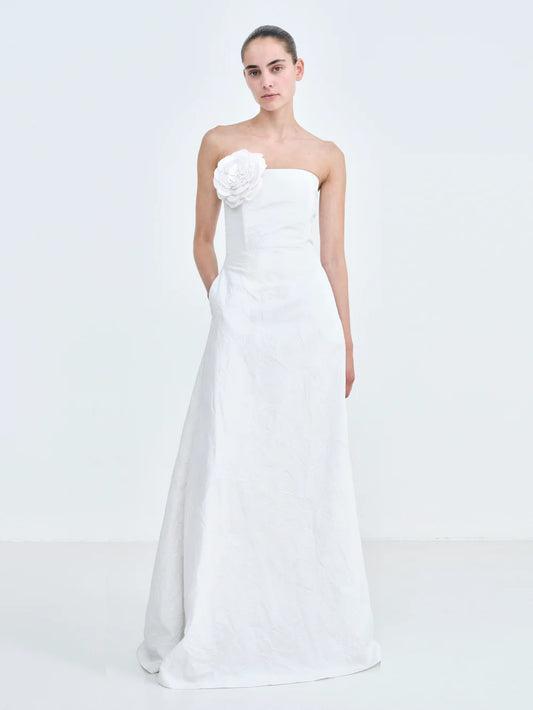 Model wearing the Caswell Bustier Wedding Dress, crafted from crisp Camellia-embossed taffeta and adorned with a hand-embroidered rose appliqué at the bodice. A romantic, floor-length gown perfect for a standout bridal look. Available at Georgette bridal boutique in Brussels and online at georgettebridal.com.