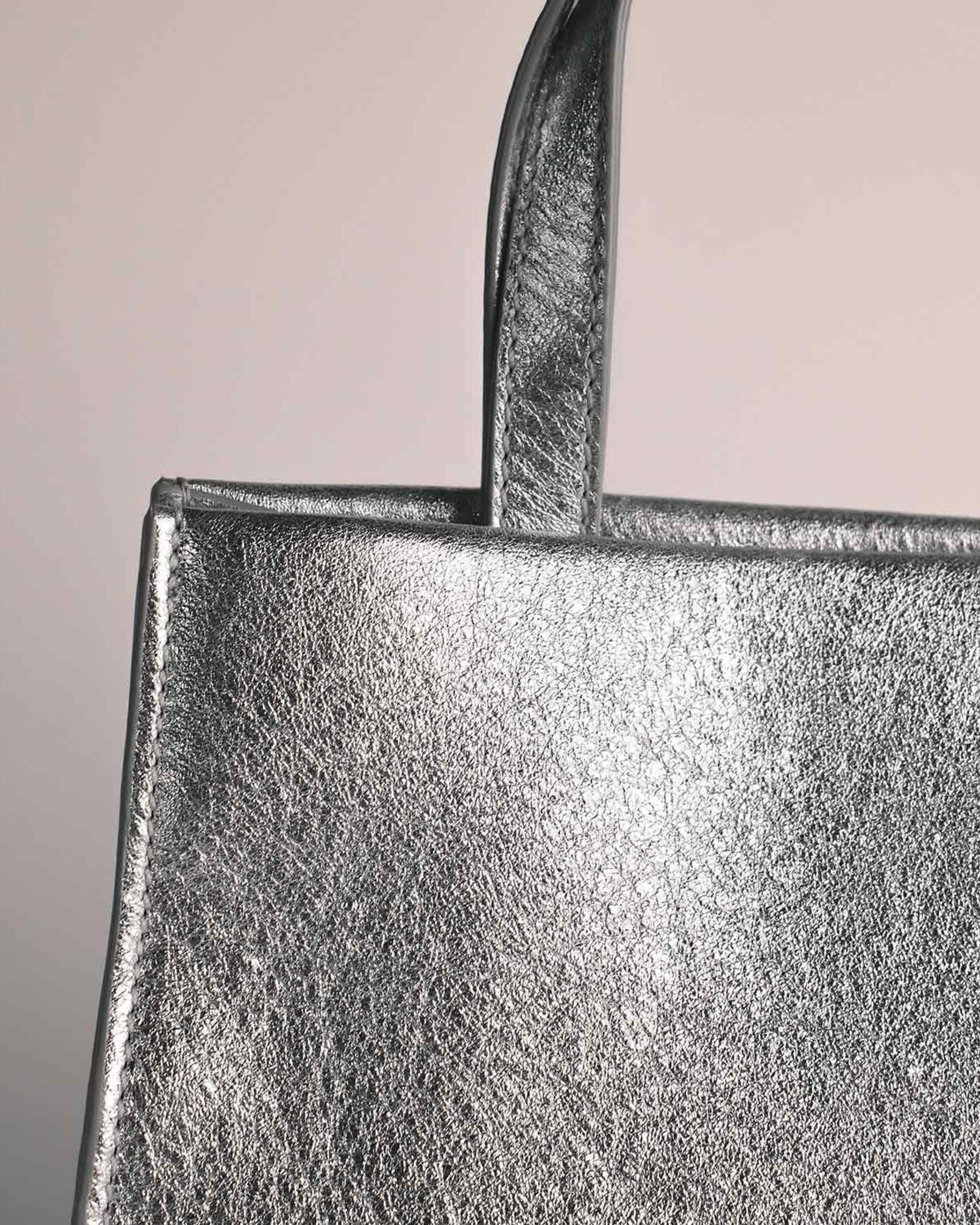 Close-up of silver leather mini bag by Voort Studio with top handle detail, available at Georgette bridal boutique in Brussels and online at georgettebridal.com