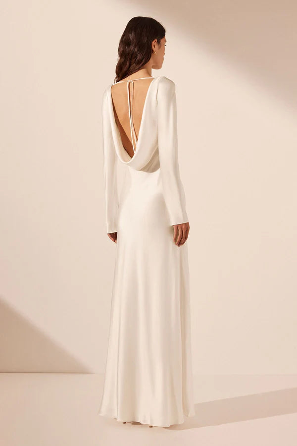 Back view, elegant silk satin maxi wedding dress with a boat neckline, long sleeves, tapered lace details, a low cowl back, and a subtle side split. Designed for timeless, understated luxury. Available at Georgette bridal boutique in Brussels and online at georgettebridal.com.