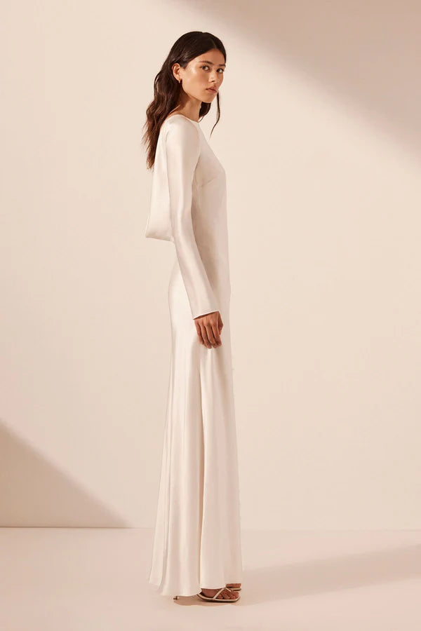 Side view, elegant silk satin maxi wedding dress with a boat neckline, long sleeves, tapered lace details, a low cowl back, and a subtle side split. Designed for timeless, understated luxury. Available at Georgette bridal boutique in Brussels and online at georgettebridal.com.