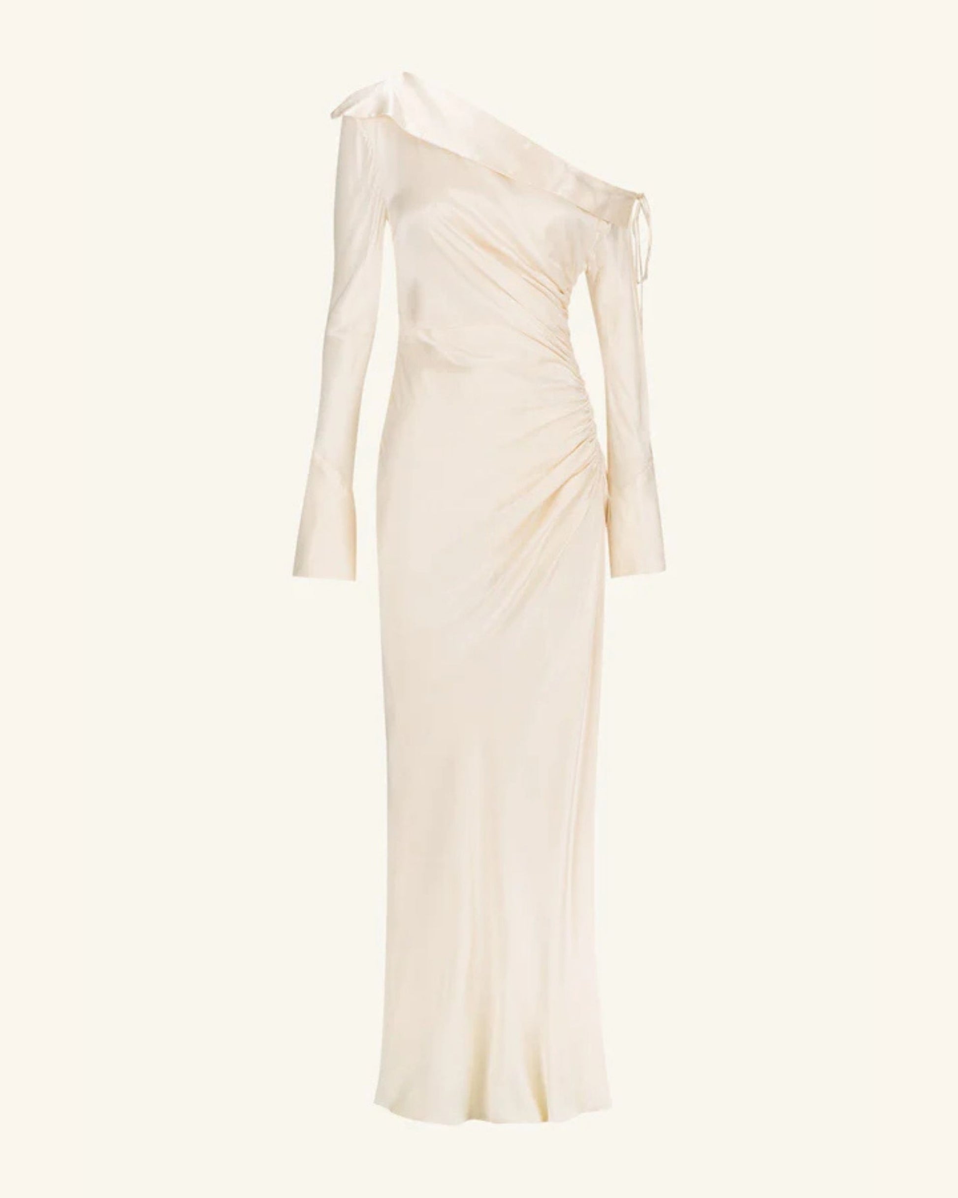 A cream satin wedding dress with an asymmetrical neckline, ruched side, cuffed sleeves with ties, and a maxi skirt with a front split. Available at Georgette bridal boutique in Brussels and online at georgettebridal.com.