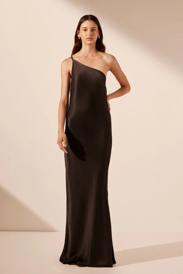Model wearing a striking black asymmetrical one-shoulder maxi dress with an open cowl back, made from sustainable LENZING™ ECOVERO™ viscose with a satin finish. Available at Georgette bridal boutique in Brussels and online at georgettebridal.com.