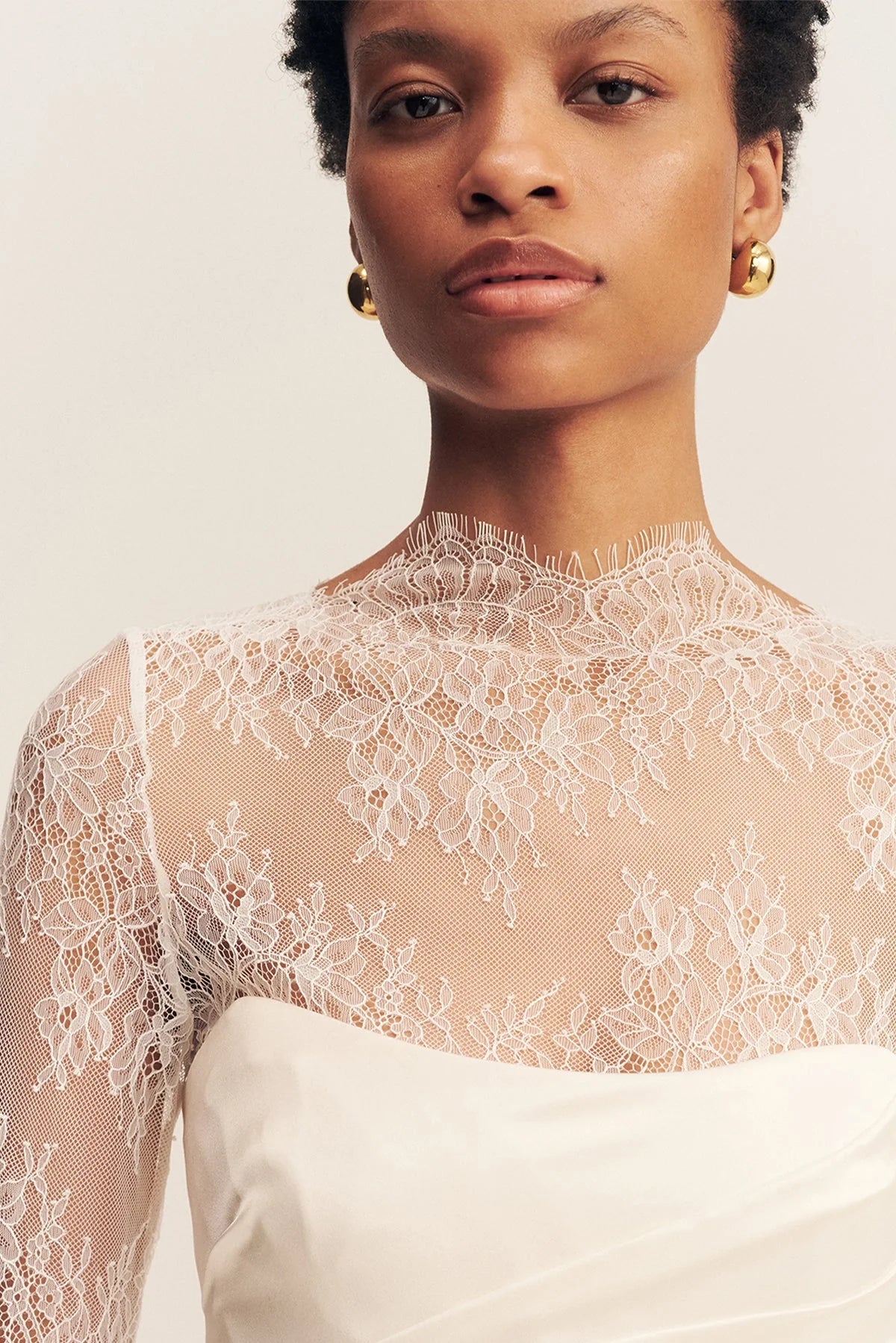 Close-up of the Lambent Lace Long Sleeve Bridal Bodysuit with intricate lace detailing and a high neckline, offering a timeless and sophisticated bridal look. Available at Georgette bridal boutique in Brussels and online at georgettebridal.com.