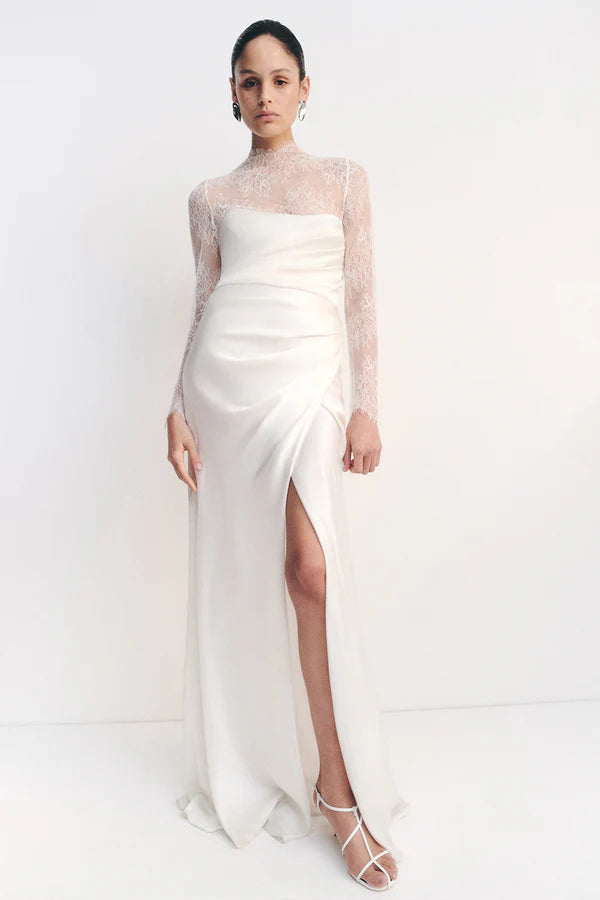 Model wearing the Lambent Lace Long Sleeve Bridal Bodysuit with intricate lace detailing and a high neckline, offering a timeless and sophisticated bridal look. Available at Georgette bridal boutique in Brussels and online at georgettebridal.com.