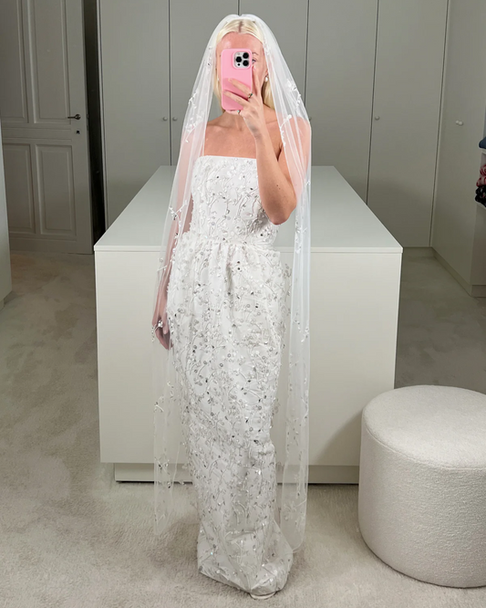 Bride wearing the Bernadette Little Flower embroidered bridal veil, available at Georgette bridal boutique in Brussels. The long veil features delicate ivory and silver floral embroidery on soft tulle.
