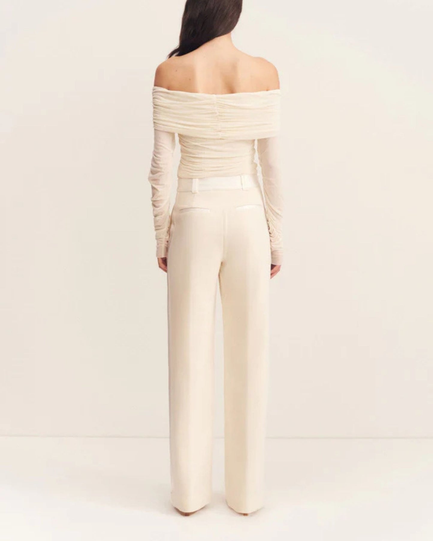 Back view of the Mira Long Sleeve Off Shoulder Top in ivory - a sheer mesh top with an off-shoulder neckline, long sleeves, and ruched side seams, creating a sculpted silhouette, available at Georgette bridal boutique in Brussels and online at georgettebridal.com.