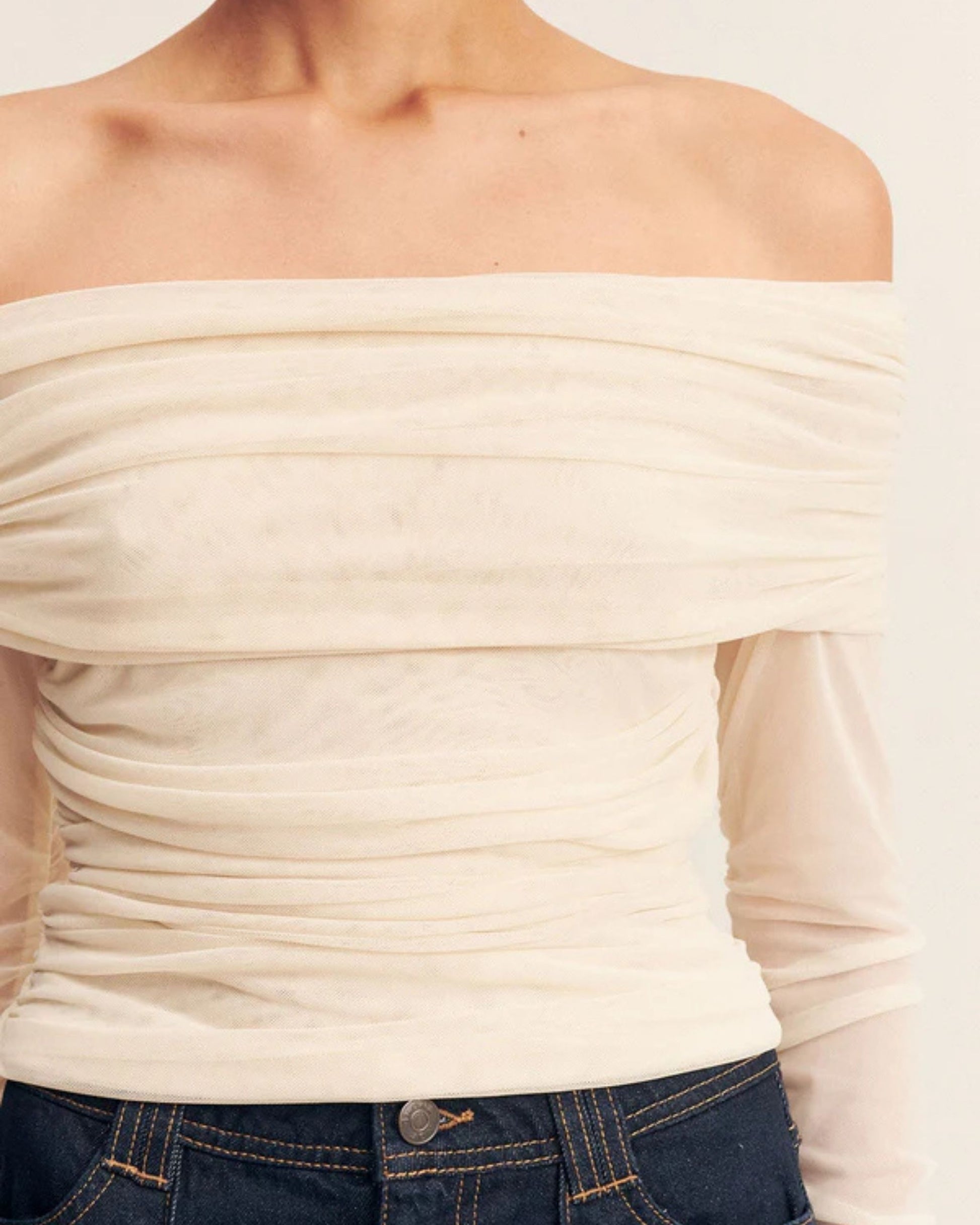Close-up of the Mira Long Sleeve Off Shoulder Top in ivory - a sheer mesh top with an off-shoulder neckline, long gathered sleeves, and ruched side seams, creating a sculpted, elegant silhouette, available at Georgette bridal boutique in Brussels and online at georgettebridal.com.