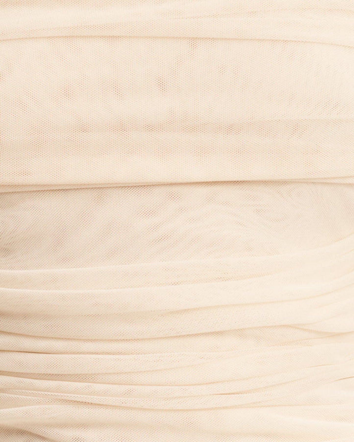 Fabric focus of Mira Long Sleeve Off Shoulder Top in ivory - a sheer mesh top with an off-shoulder neckline, long sleeves, and ruched side seams, creating a sculpted silhouette, available at Georgette bridal boutique in Brussels and online at georgettebridal.com.