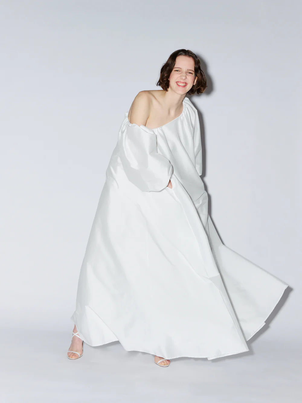 Model wearing the Nathalie one-shoulder wedding dress in signature taffeta, featuring a sculptural neckline, voluminous sleeve, and a dramatic floor-length silhouette. Available at Georgette bridal boutique in Brussels and online at georgettebridal.com.