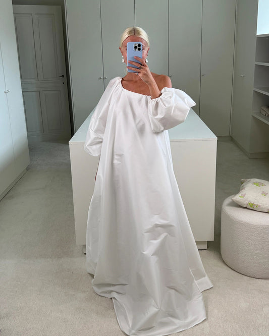 Model wearing the Nathalie one-shoulder wedding dress in signature taffeta, featuring a sculptural neckline, voluminous sleeve, and a dramatic floor-length silhouette. Available at Georgette bridal boutique in Brussels and online at georgettebridal.com.